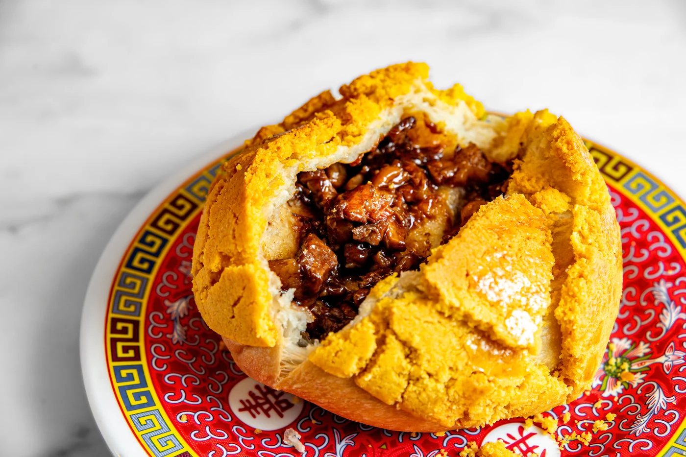 Official photograph of a pineapple-topped pork bun cut open to show char siu filling.